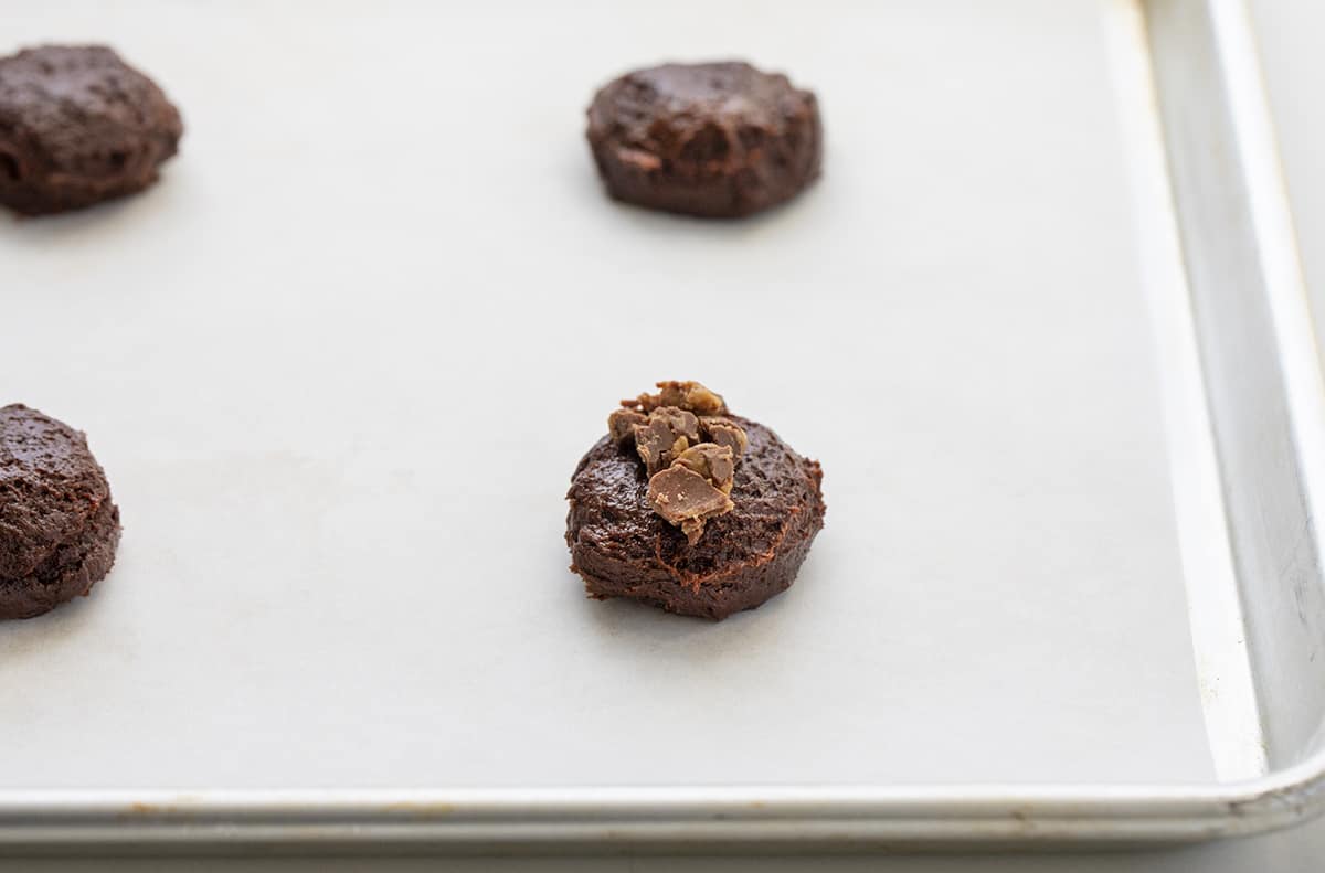 Chocolate Reese's Cake Mix Cookies are cookies made with chocolate cake mix and topped with chopped mini Reese's peanut butter cups. I love from-scratch cookies (there are hundreds on my website!) but also love the convenience of grabbing a cake mix! Raw batter with a few reeses sprinkled on top before baking.