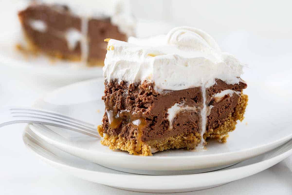 Chocolate Caramel Cheesecake Pie is a no-bake dessert with a homemade graham cracker crust filled with layers of chocolate cheesecake, marshmallow, fudge, and caramel. Phish Food, Phish Food Pie, Chocolate Marshmallow Caramel Pie, No Bake Pie, Dessert, Chocolate Pie, recipes, i am baker, iambaker Chocolate Caramel Marshmallow Cheesecake Pie with One Bite Removed Showing Caramel and Marshmallow Inside