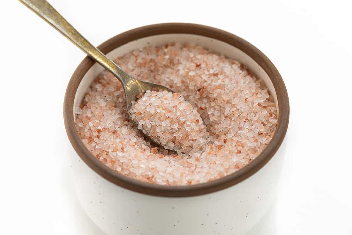 I often get asked about the role of salt in baking, especially kosher as that is what I prefer. Salt is not just a flavor enhancer, but it also plays a vital role in the baking process. In fact, it's one of the four essential ingredients in bread - flour, salt, yeast, and water. I'd love to share which salt I use, and why different salts can't be used interchangeably! A Container of Himalayan Salt with a Spoon in it.