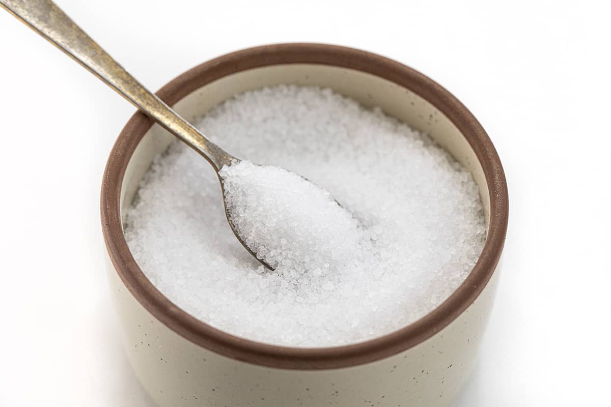 I often get asked about the role of salt in baking, especially kosher as that is what I prefer. Salt is not just a flavor enhancer, but it also plays a vital role in the baking process. In fact, it's one of the four essential ingredients in bread - flour, salt, yeast, and water. I'd love to share which salt I use, and why different salts can't be used interchangeably! A Container of Sea Salt with a Spoon in it.