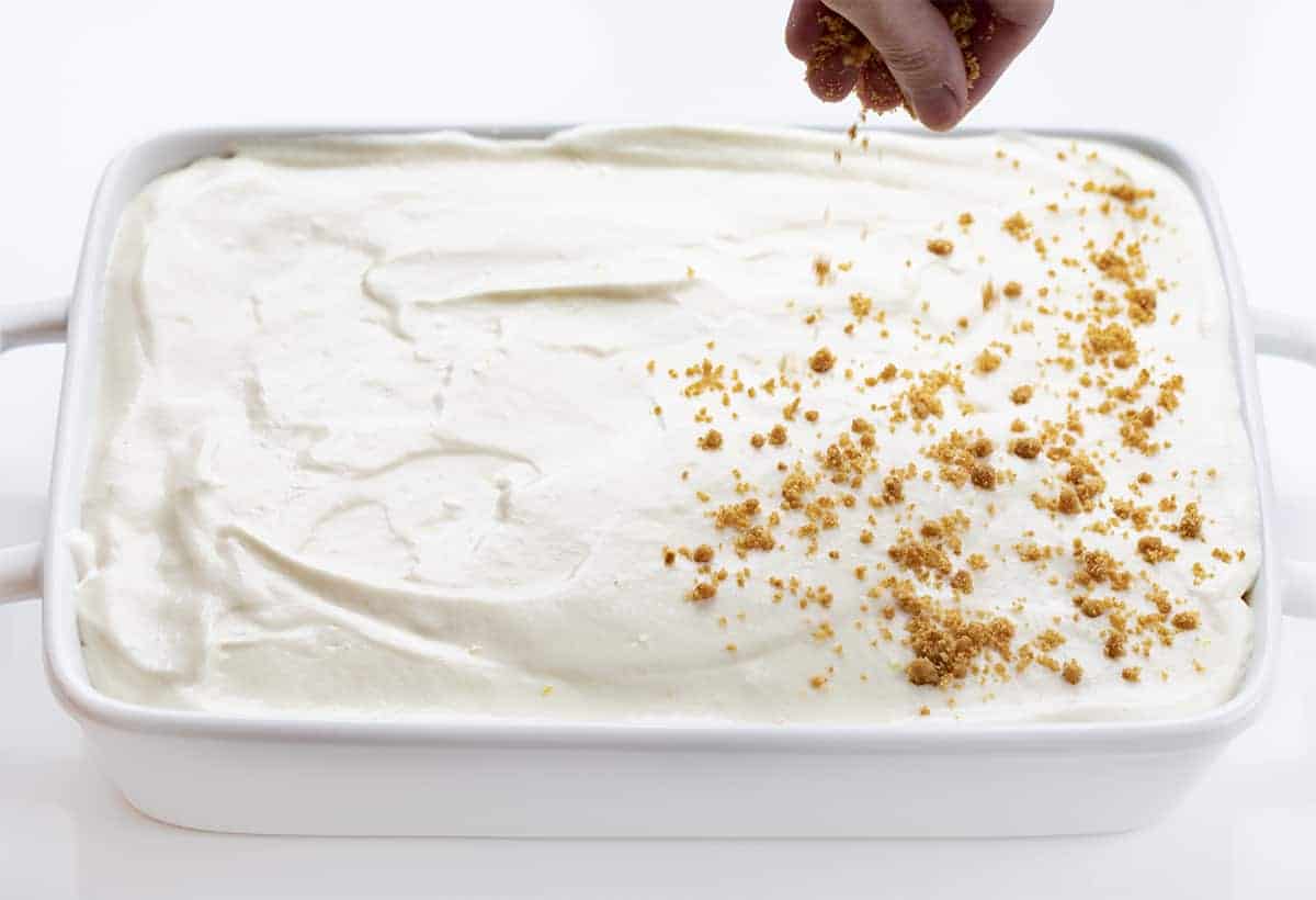Woolworth Icebox Cheesecake Recipe is a light and fluffy, no-bake dessert with a hint of lemon flavor on top of a graham cracker crust. Woolworth Recipe, Cloud Cheesecake, Icebox Cake, BBQ, Summer Desserts, Dessert, Old Fashioned Dessert, Vintage Cake, i am baker, iambaker Adding Graham Cracker to Woolworth Icebox Cake Recipe