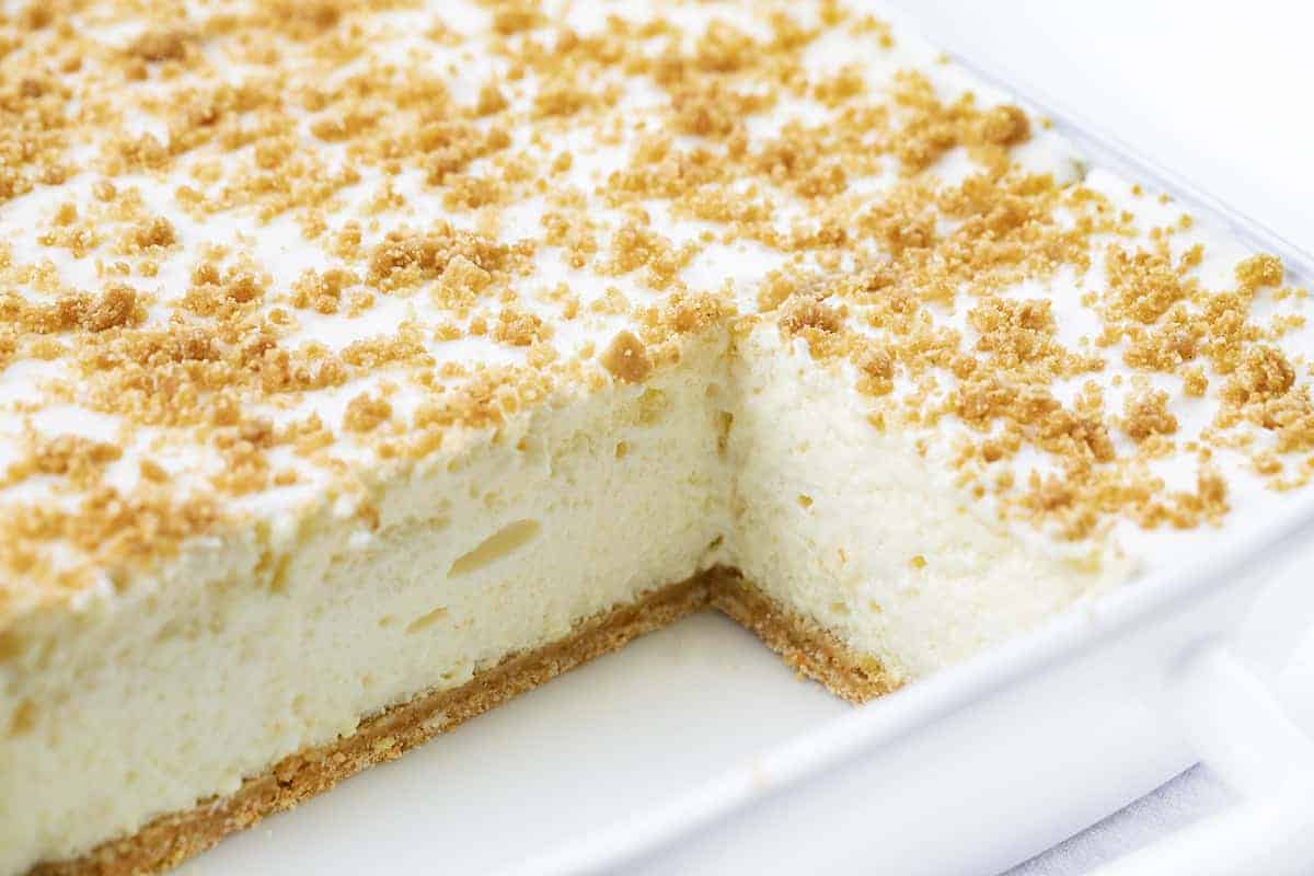 Woolworth Icebox Cheesecake Recipe is a light and fluffy, no-bake dessert with a hint of lemon flavor on top of a graham cracker crust. Woolworth Recipe, Cloud Cheesecake, Icebox Cake, BBQ, Summer Desserts, Dessert, Old Fashioned Dessert, Vintage Cake, i am baker, iambaker Cut Into Woolworth Icebox Cake Recipe